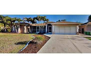 Charming single-story home with a well-manicured lawn, palm trees, and a spacious driveway at 23344 Van Buren Ave, Punta Gorda, FL 33980