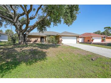 Charming single-story home with a well-maintained lawn and a large shade tree in a sunny neighborhood at 2751 S Cranberry Blvd, North Port, FL 34286
