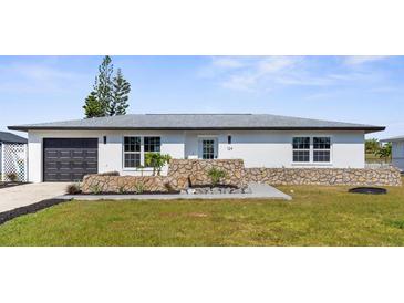 Charming one-story home featuring a decorative stone facade, well-manicured lawn, and a dark gray garage door at 124 Rotonda Cir, Rotonda West, FL 33947