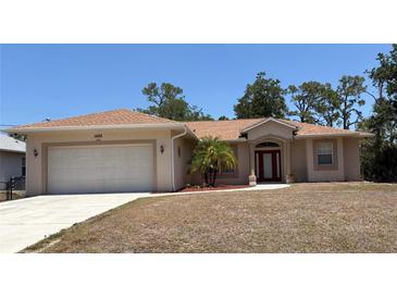 Charming single-story home featuring a well-maintained lawn, mature palm tree, and inviting front entrance at 1488 Squaw Ln, North Port, FL 34286