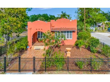 Charming coral stucco home featuring an arched entryway, red tile roof and well-manicured landscaping at 2002 Central Ave, Sarasota, FL 34234