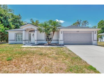 Charming single-story home featuring a two-car garage and a well-maintained lawn with mature landscaping at 4129 Palisades Ave, North Port, FL 34287
