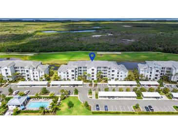 Beautiful aerial view of the complex with parking, pool, and golf course and wetlands in the background at 14061 Heritage Landing Blvd # 445, Punta Gorda, FL 33955