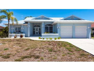 Charming light blue single-story home with a well-manicured lawn and a two-car garage at 1711 Boca Raton Ct, Punta Gorda, FL 33950