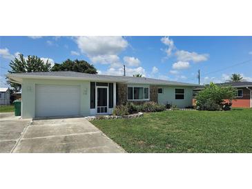 Charming single-story home with a well-maintained lawn, stone accents, and attached garage at 570 Mimosa Nw Ave, Port Charlotte, FL 33952