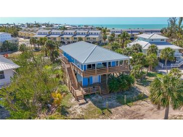 Stunning elevated beach house with wood decks, lush landscaping, and a metal roof with ocean view at 9390 Little Gasparilla Island, Placida, FL 33946
