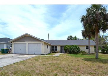 Single story home with a two car garage and a lawn at 21161 Knollwood Ave, Port Charlotte, FL 33952