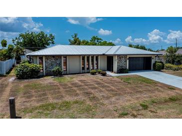 Charming single-story home featuring a metal roof, stone accents, and a convenient attached garage at 543 Mayview Nw Ave, Port Charlotte, FL 33952