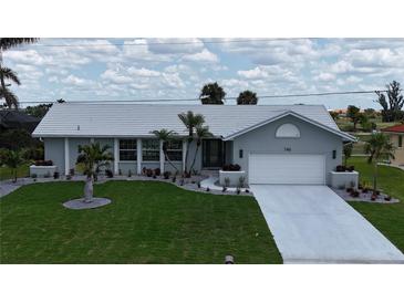 Charming one-story home featuring a well-manicured lawn, mature palm trees and a white tile roof at 745 Monaco Dr, Punta Gorda, FL 33950