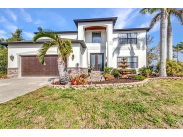 Stunning two-story home with a well-manicured lawn, fountain, and lush landscaping at 9239 Impala Cir, Port Charlotte, FL 33981