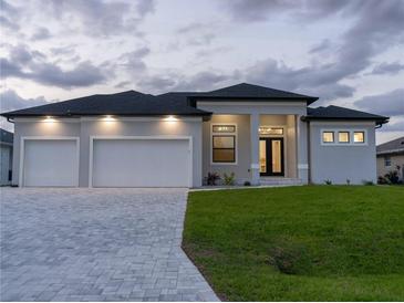 Beautiful single-story home featuring a three-car garage, landscaped yard, and neutral color scheme at 15504 Melport Cir, Port Charlotte, FL 33981