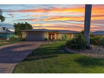 Beautiful sunset illuminates this waterfront property with lush landscaping and a brick paved driveway at 2100 Via Esplanade, Punta Gorda, FL 33950