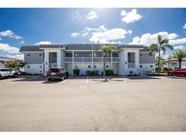 Condominium building featuring a well-maintained exterior, ample parking, and lush landscaping with palm trees under a bright sky at 22375 Edgewater Dr # 123, Punta Gorda, FL 33980