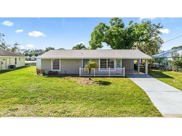 Charming single-story home with a well-maintained lawn, mature trees, and a welcoming front entrance at 2331 Cannolot Blvd, Port Charlotte, FL 33948