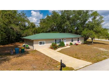 Beautifully landscaped single-story home with a lush green metal roof at 4009 Yucatan Cir, Port Charlotte, FL 33948