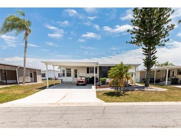 Charming single-story home with a covered carport, lush trees, and a well-manicured lawn at 713 Riverview Cir, North Port, FL 34287