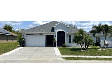 Charming single-story home with well-manicured lawn, black door, and attached garage at 10068 Winding River Rd, Punta Gorda, FL 33950