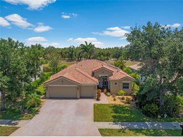 Beautiful home with a tile roof, a three car garage and mature landscaping at 11982 Granite Woods Loop, Venice, FL 34292