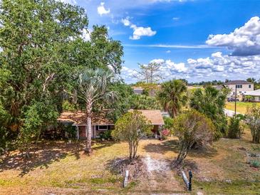 Charming home featuring mature trees, a brick facade, and a cozy front porch at 12018 Saragossa Ln, North Port, FL 34287