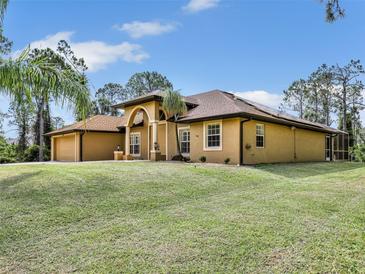 Sprawling tan home featuring a lush green lawn, front-facing garage, and an elegant arched entrance at 8377 Mambo Ave, North Port, FL 34291