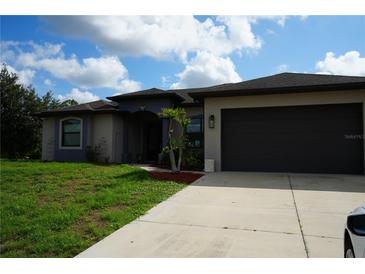 Beautiful one-story home featuring a gray stucco exterior, a driveway, and manicured lawn at 1480 Wise Dr, North Port, FL 34286