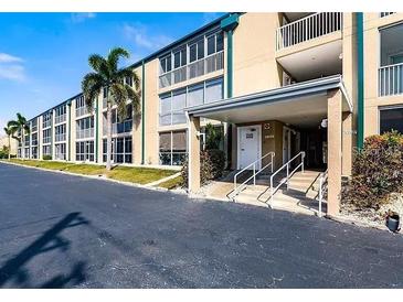 Low-rise building featuring a covered entry and well-maintained landscaping with palm trees at 150 Harborside Ave # 124, Punta Gorda, FL 33950