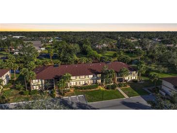 Inviting condo building surrounded by lush greenery and palm trees at 19505 Quesada Ave # M104, Port Charlotte, FL 33948