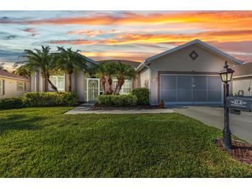 Charming single-story home featuring lush lawn, mature landscaping, and a two-car garage at sunset at 24371 Folkstone Ave, Punta Gorda, FL 33980
