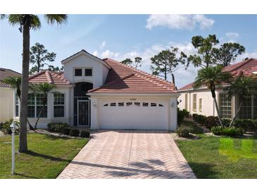 Charming single-story home featuring a well-manicured lawn and a brick driveway leading to a two-car garage at 26089 Seminole Lakes Blvd, Punta Gorda, FL 33955