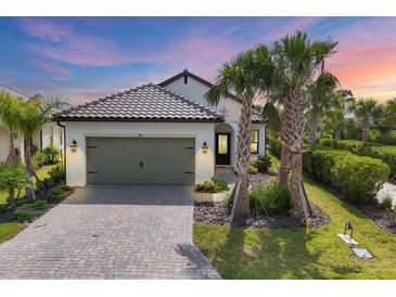 Charming single-story home with a two-car garage, a brick driveway, and lush tropical landscaping at 281 Potenza Loop, Nokomis, FL 34275