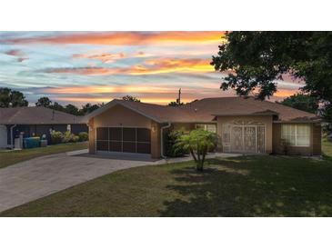 Charming single-story home with well-manicured lawn, attached garage, and security gate at entry under a colorful sunset sky at 78 Zenith St, Port Charlotte, FL 33954
