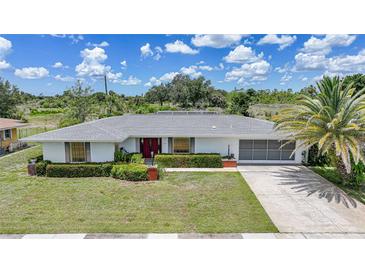 Charming single-story home featuring a well-manicured lawn, tropical landscaping, and an attached two-car garage at 2193 Beacon Dr, Port Charlotte, FL 33952