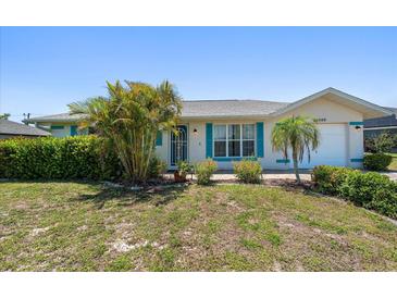 Charming single-story home featuring lush landscaping, turquoise shutters, and a well-maintained lawn at 25449 Doredo Dr, Punta Gorda, FL 33955