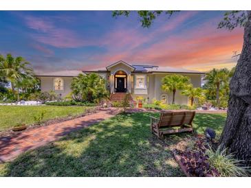 Charming home with a lush front yard, brick walkway, mature trees and manicured landscaping at 6242 Tropicaire Blvd, North Port, FL 34291