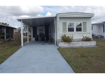 Cozy mobile home featuring a covered parking area and a well-maintained lawn at 6832 Holo Ct, North Port, FL 34287
