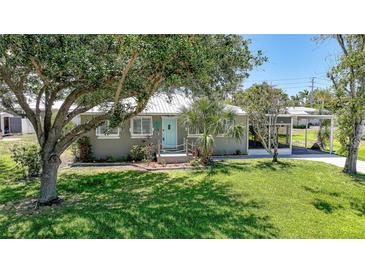 Charming home featuring a lush green lawn, mature trees, and a quaint entrance with a light blue door at 809 Kings Ct, Punta Gorda, FL 33950