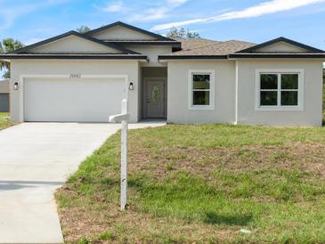 Charming single-Gathering home with a two-car garage and well-manicured lawn on a sunny day at 19092 Woodbine Ave, Port Charlotte, FL 33954