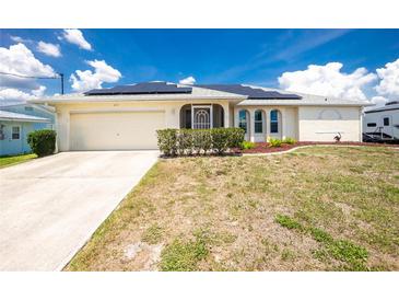 Charming single-story home featuring a two-car garage, solar panels, and a well-maintained lawn at 211 E Tarpon Nw Blvd, Port Charlotte, FL 33952