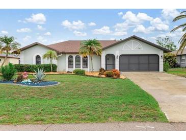 Charming single-story home with well-manicured lawn and tropical landscaping, enhancing curb appeal at 26177 Madras Ct, Punta Gorda, FL 33983