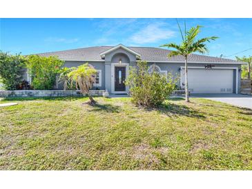 Charming single-story home featuring a well-manicured lawn and tropical landscaping, offering curb appeal at 9295 Melody Cir, Port Charlotte, FL 33981