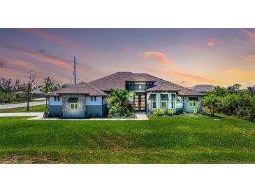 Stunning exterior with lush lawn, mature landscaping and striking architectural details at sunset at 10233 St Paul Dr, Port Charlotte, FL 33981