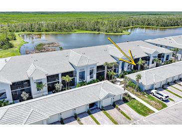 Beautiful condo complex with lake view, lush landscaping, and white tile roof at 14271 Heritage Landing Blvd # 1516, Punta Gorda, FL 33955
