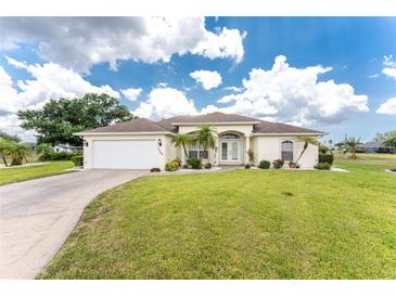 Charming single-story home featuring a well-manicured lawn and a two car garage, set under a bright sky at 2168 Calcutta Rd, Punta Gorda, FL 33983