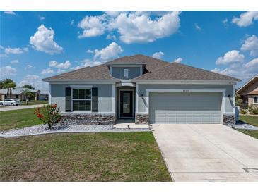 Charming single-story home with gray stucco, well-manicured lawn, stone accents, and a two-car garage at 25308 Rupert Rd, Punta Gorda, FL 33983