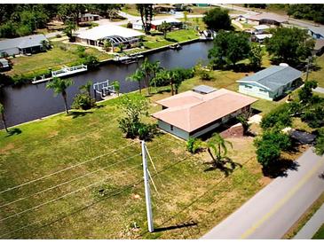 Waterfront home with boat dock on canal, surrounded by lush greenery and neighboring homes at 27193 And 27197 Voyageur Dr, Punta Gorda, FL 33983