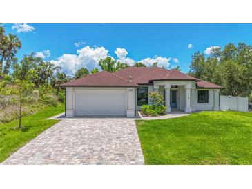 Beautiful single-story home featuring a brick driveway, lush lawn, and attached two car garage at 2955 Carmela Ave, North Port, FL 34286