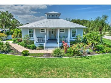 Charming single-story home with metal roof, inviting front porch, walkway, and beautifully landscaped front yard at 329 W Grace St, Punta Gorda, FL 33950