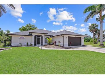 Charming home with lush lawn, freshly mulched planting beds, and a dark-colored two-car garage at 7448 S Blue Sage, Punta Gorda, FL 33955