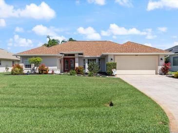 Beautiful single-story home featuring a well-manicured lawn, a two-car garage, and a lovely front yard with mature landscaping at 85 Long Meadow Ct, Rotonda West, FL 33947