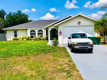 Charming home featuring a well-maintained lawn, attached garage, and lovely front yard landscaping at 1017 Guild St, Port Charlotte, FL 33952